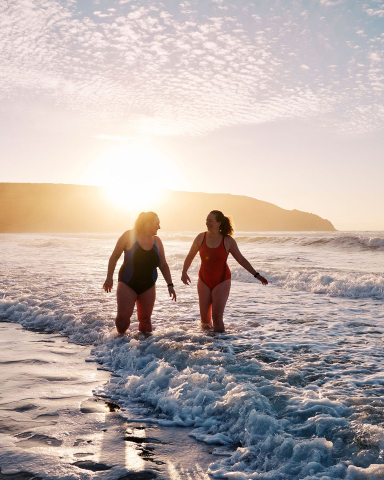 Open water swimmersby the shore at sunset.