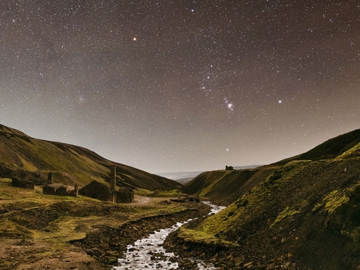 A stream winding through the mountains under a starry sky.