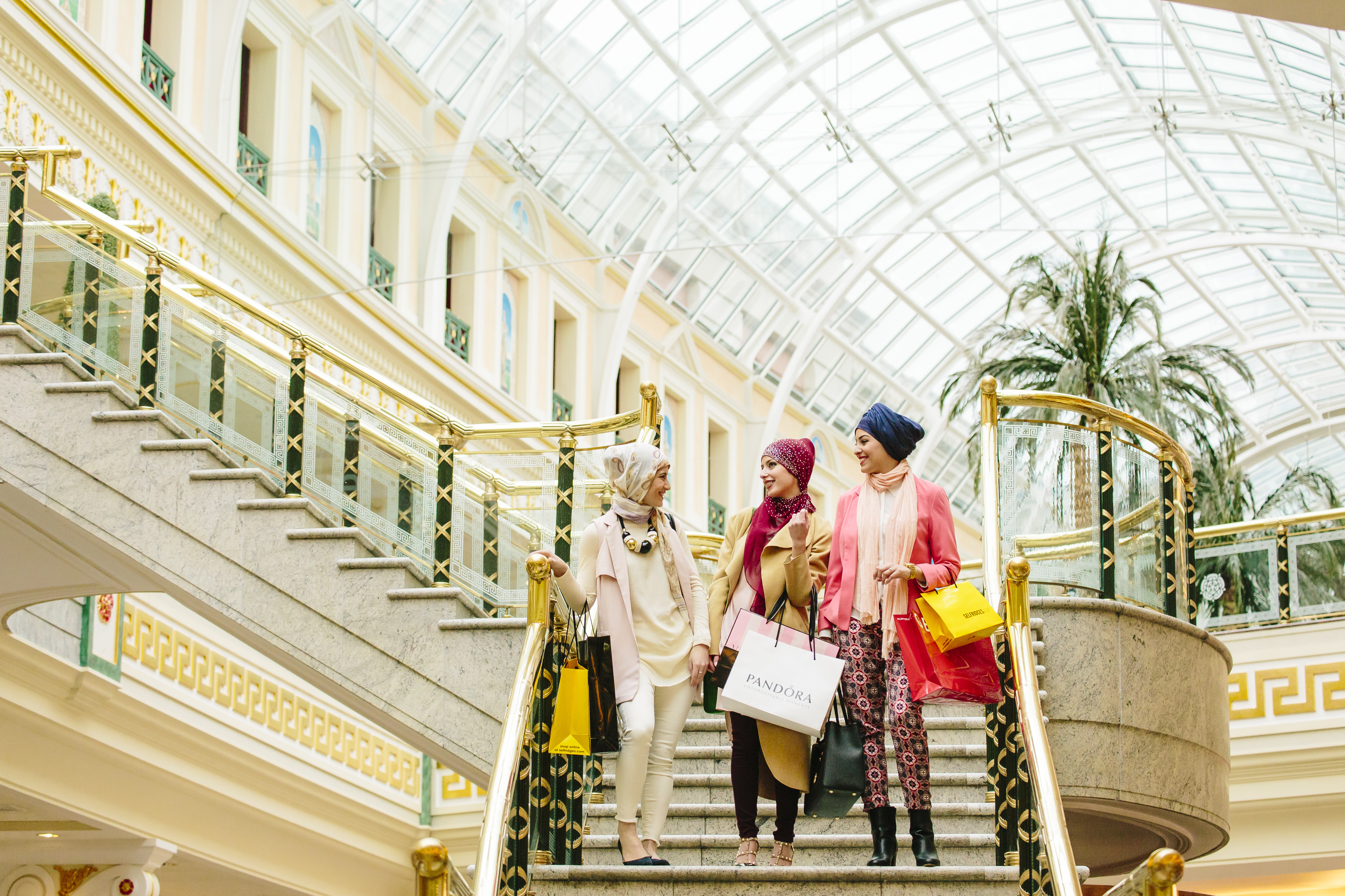 Three women, wearing scarves, walking with shopping bags