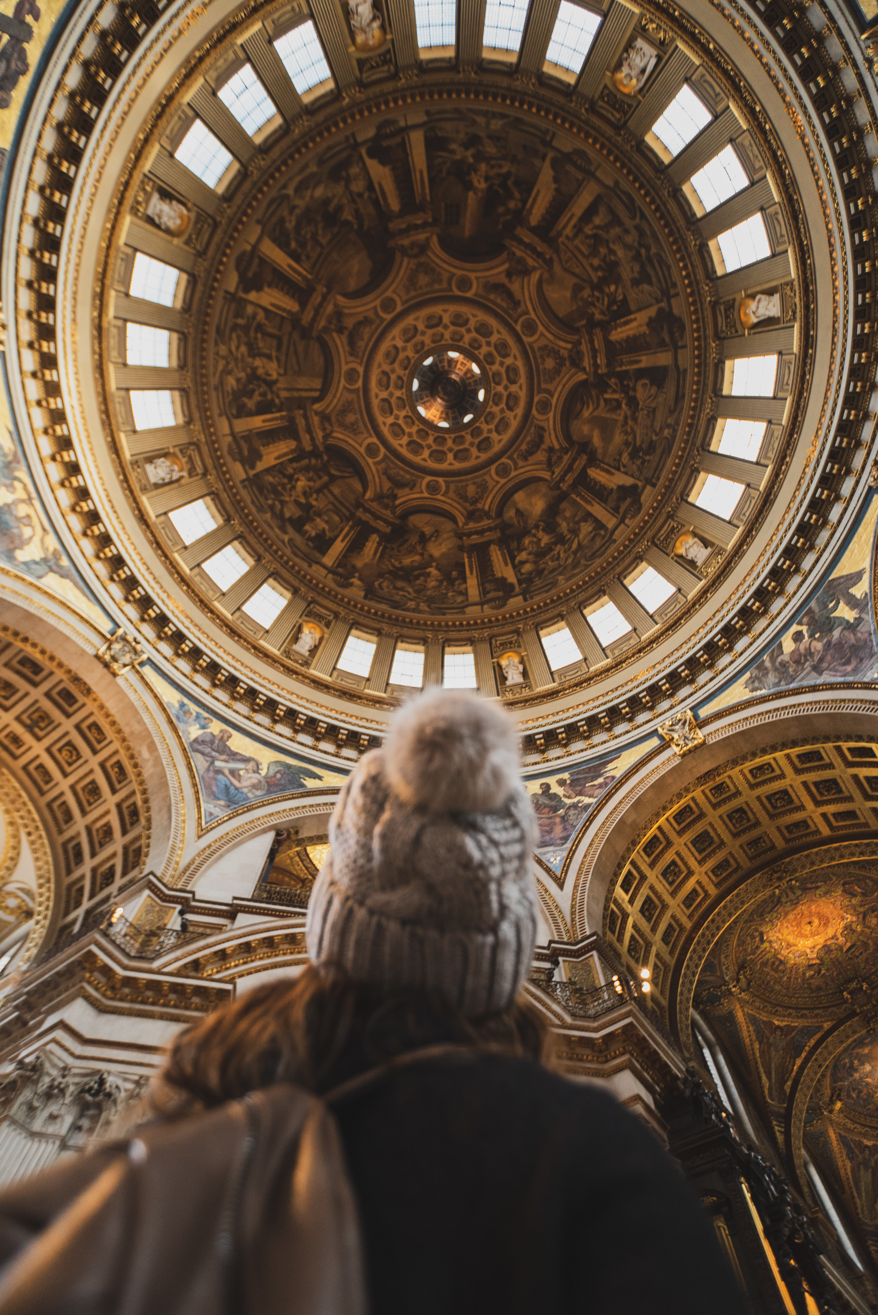 Woman in a wooly hat looking up at the ornate design of St Paul's dome