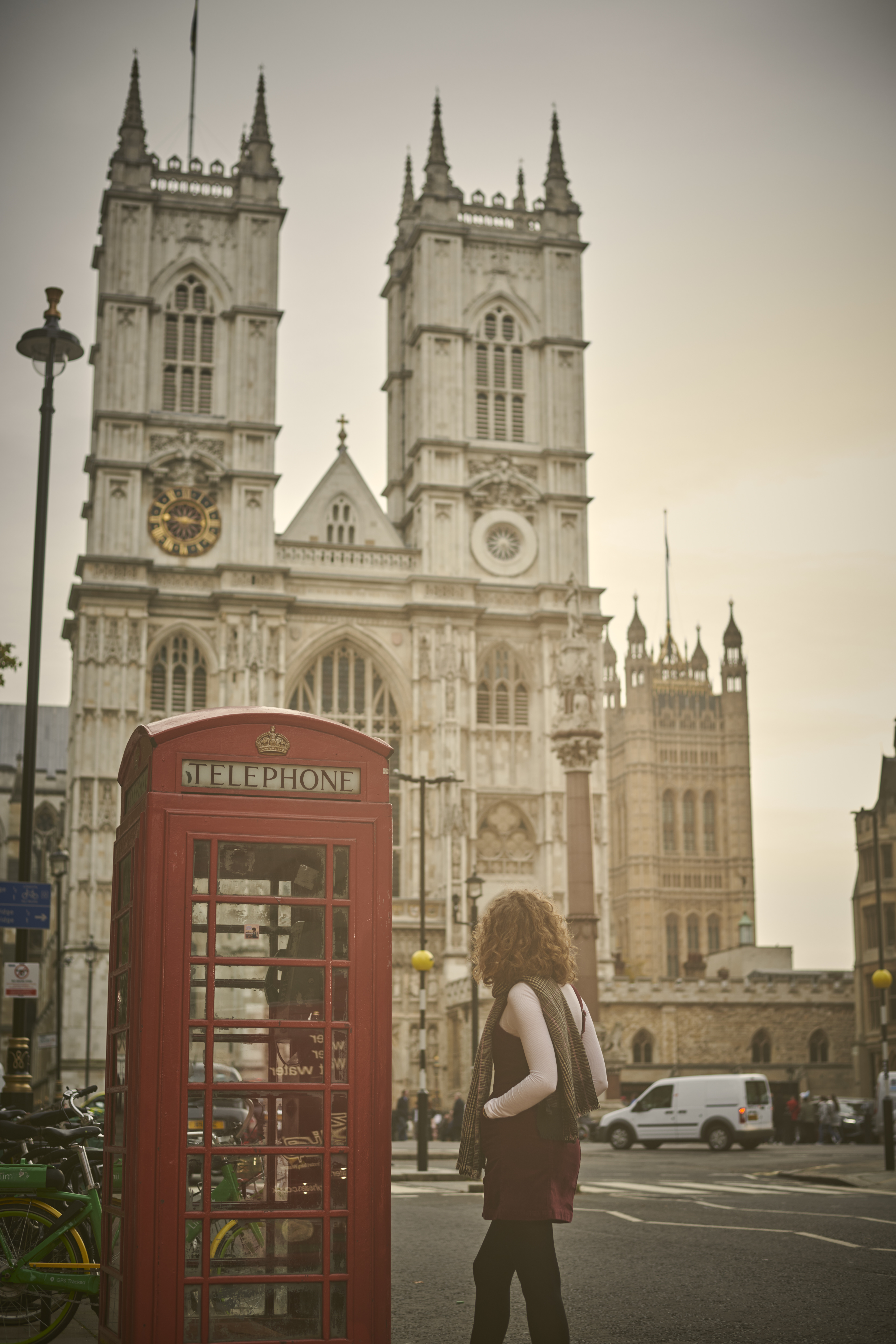 Woman stood at a red phone box in front of Westminster Abbey