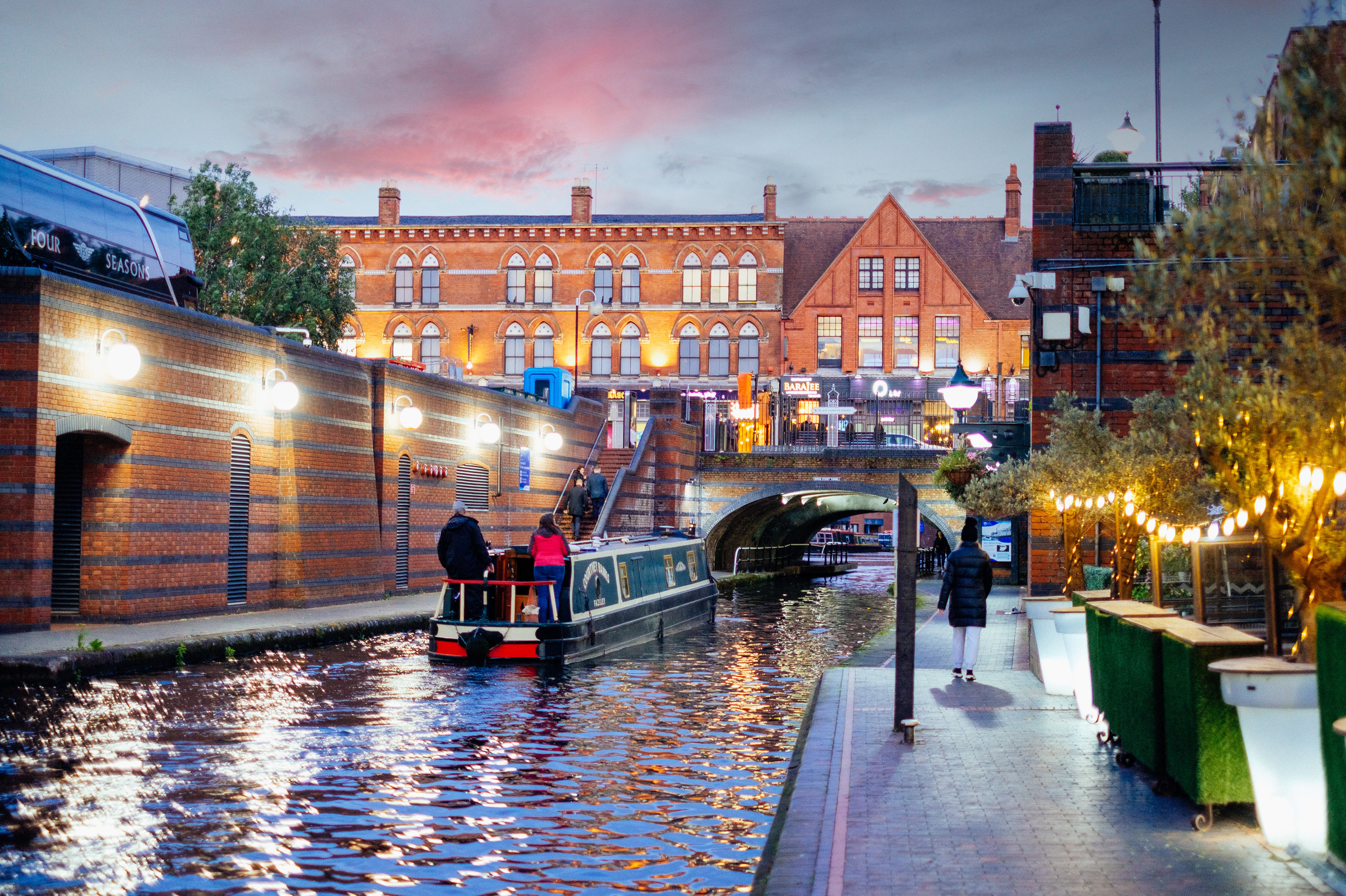Riverboat on a canal. People walking down path on Brindley Place, Birmingham, England