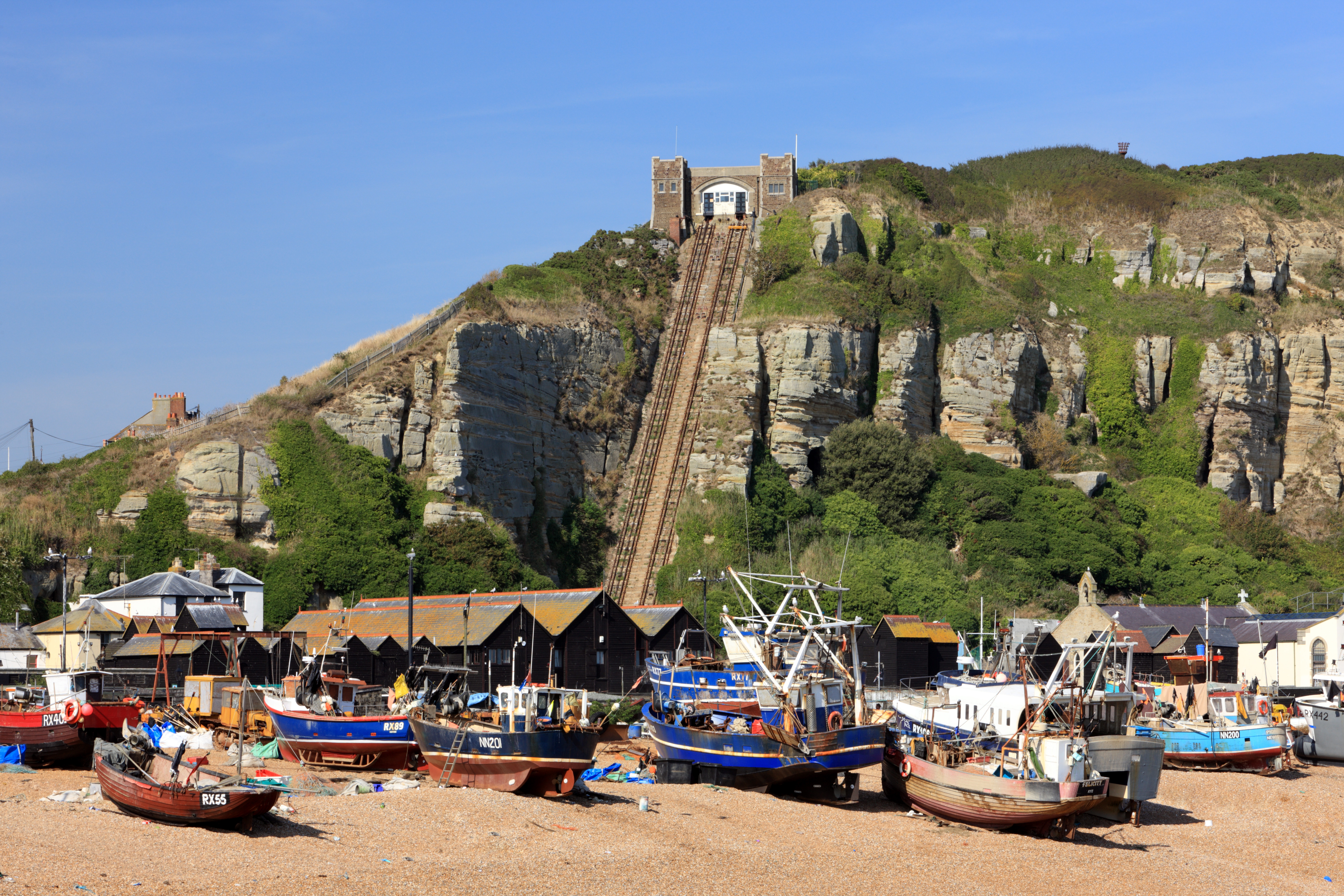 Fishing boats docked on Hastings beach with the funicular cliff railway behind