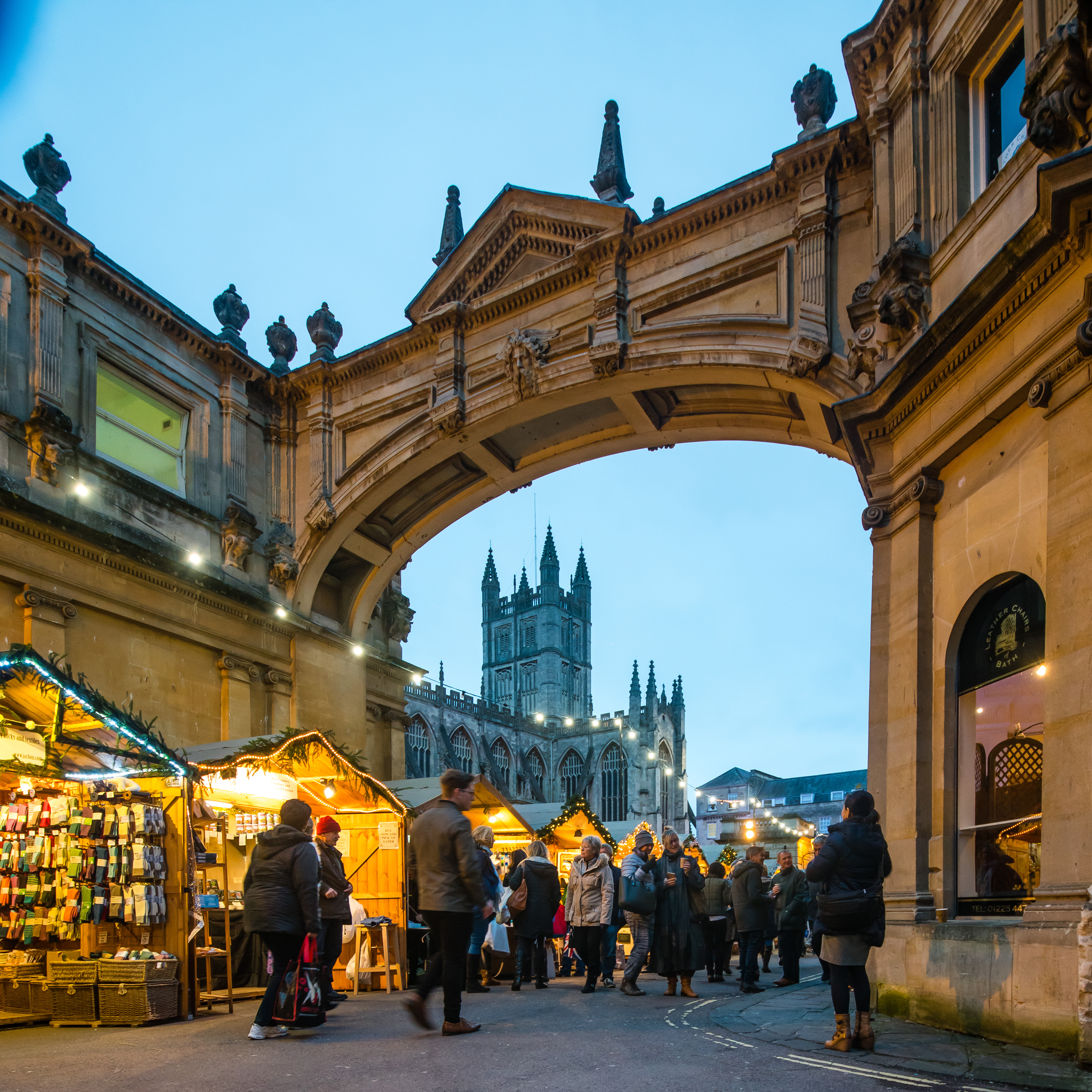 Christmas market stalls line York St in Bath with Bath Abbey in the background