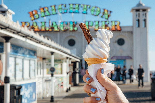 Close up of person holding ice cream cone, Brighton Palace Pier, Brighton, East Sussex, England.