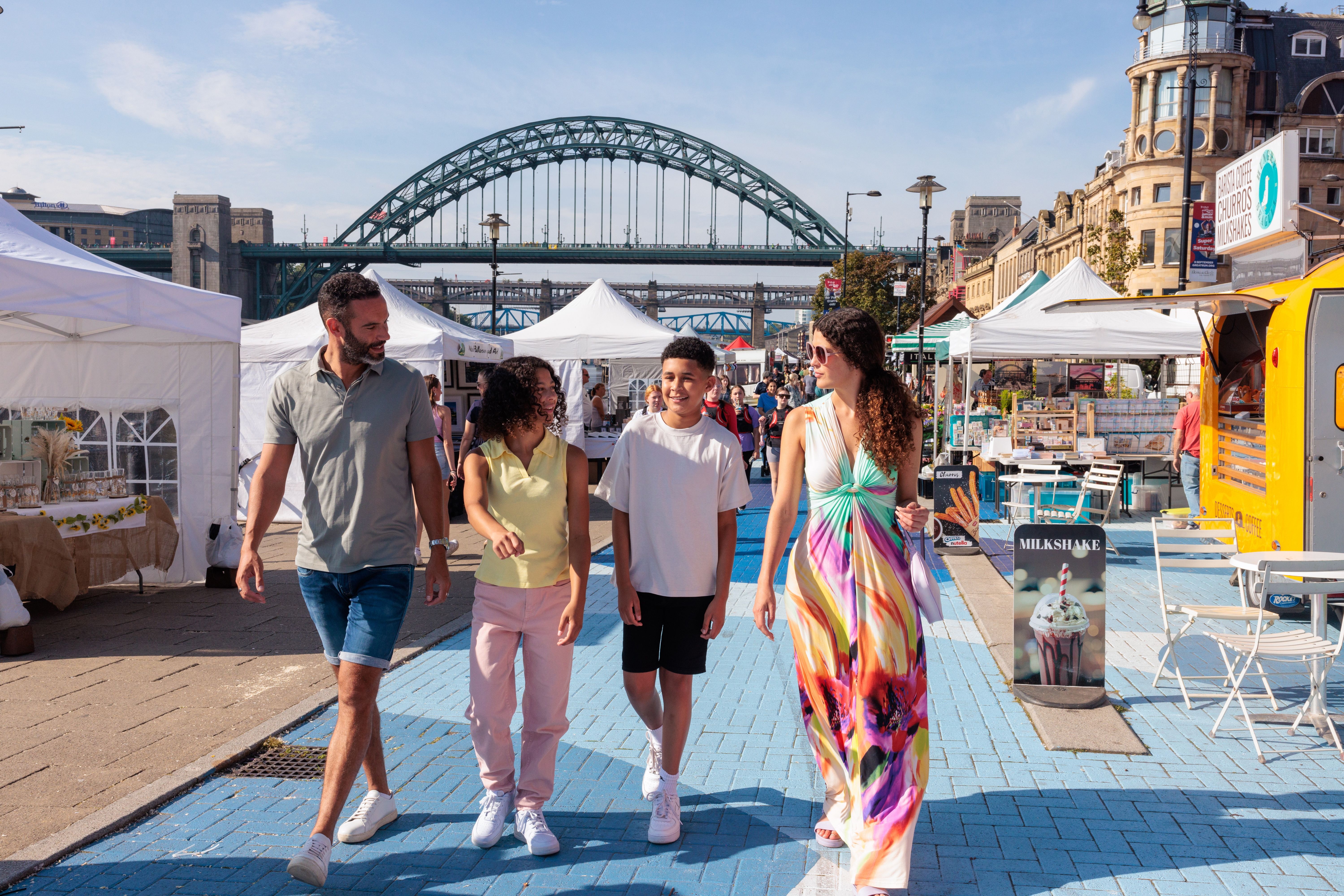 A family visit a Sunday market by the river Tyne in Newcastle upon Tyne