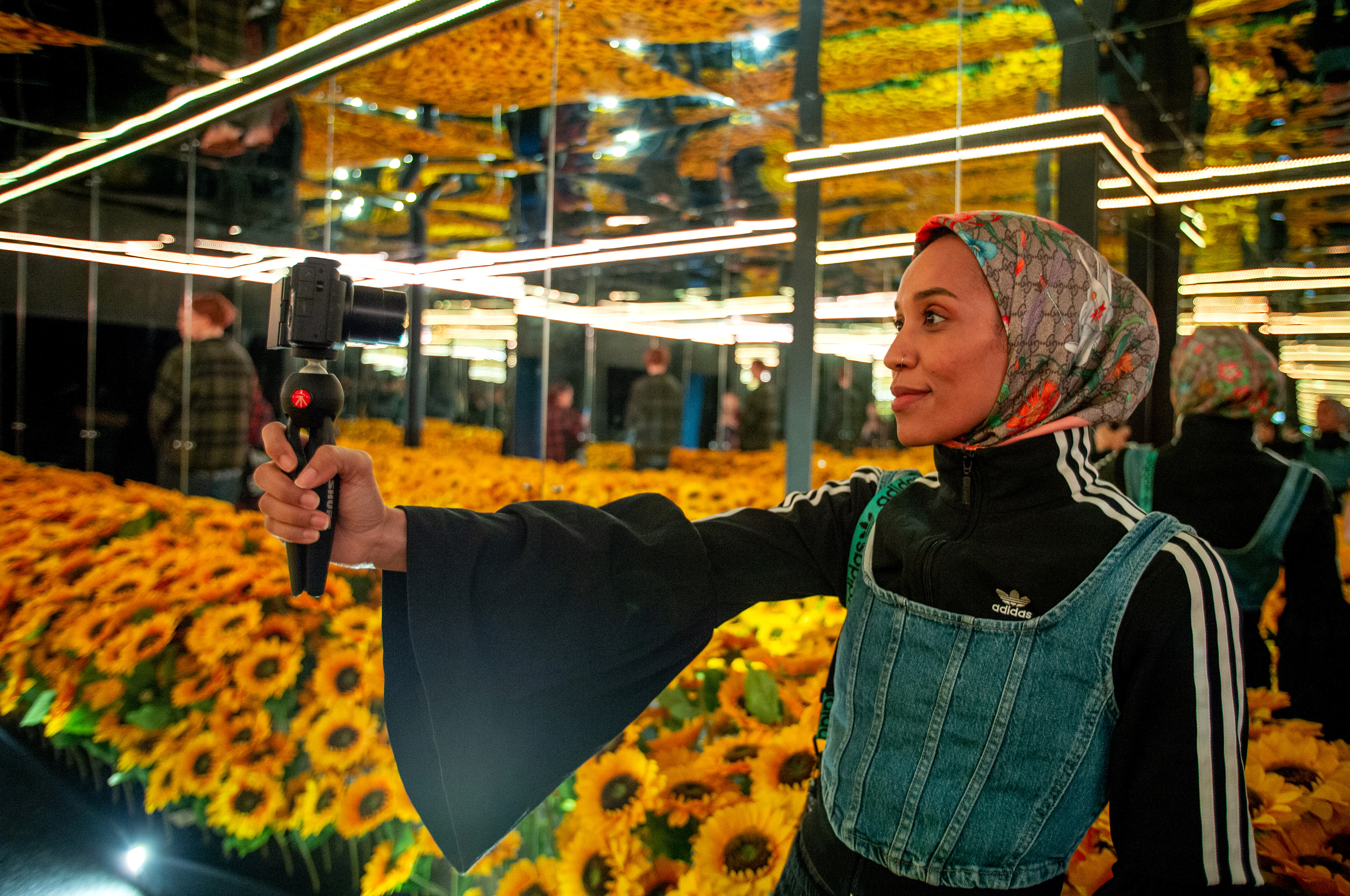 Sudanese-british poet and activist Asma Elbadawi takes a selfie with the sunflowers exhibit