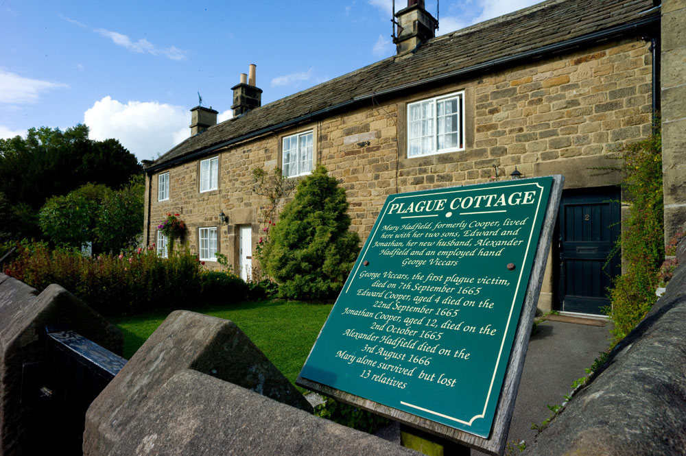 A green sign outside Eyam's 'plague cottage' listing the residents who died during the outbreak