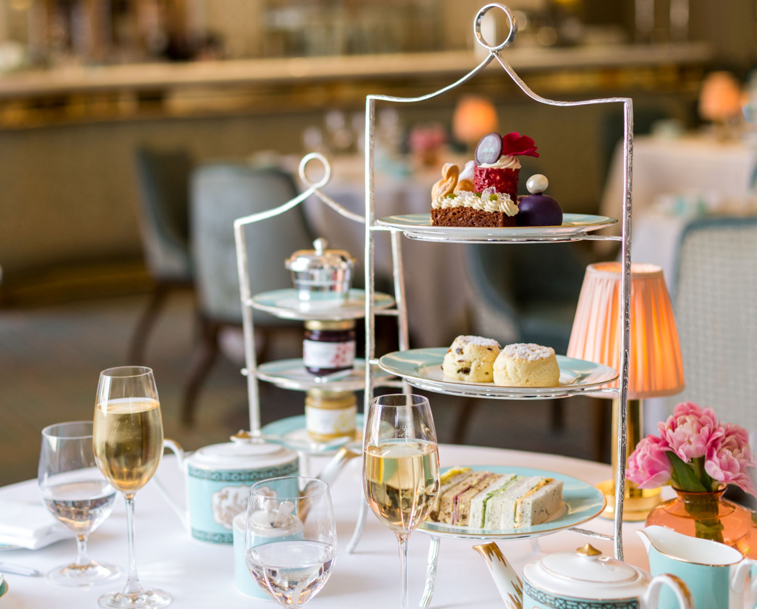 Three-tiered afternoon tea stand with filled champagne glasses at Fortnum and Mason