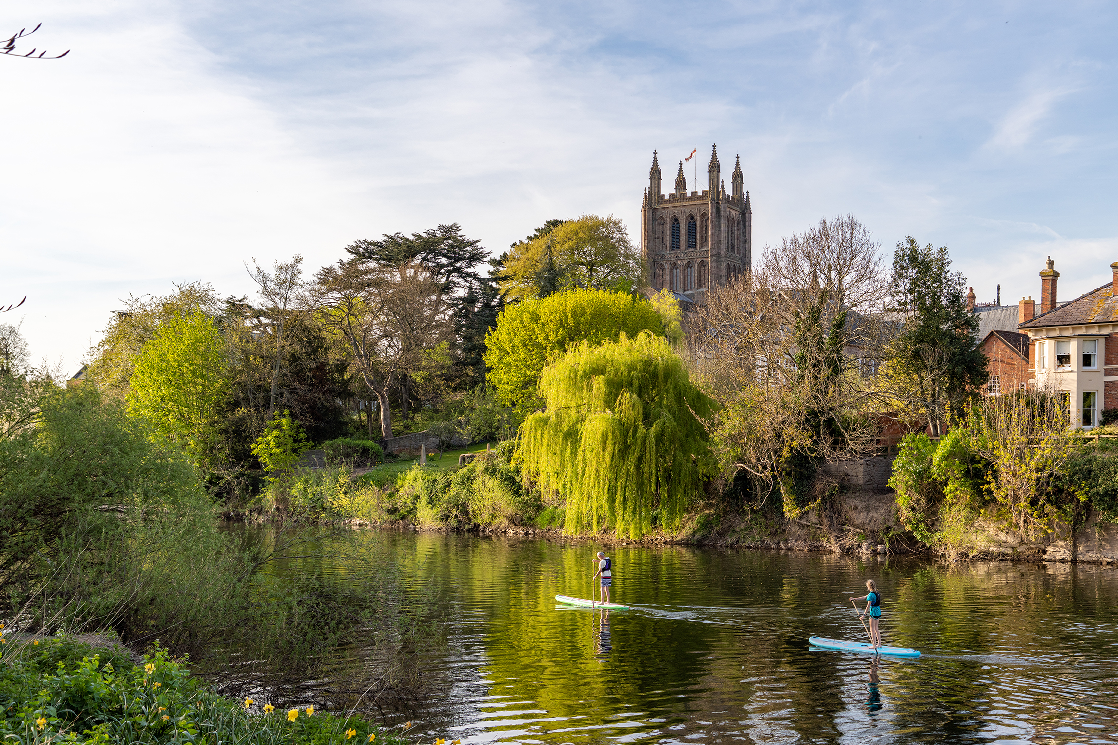 View towards Hereford Cathedral across river with paddleboarders