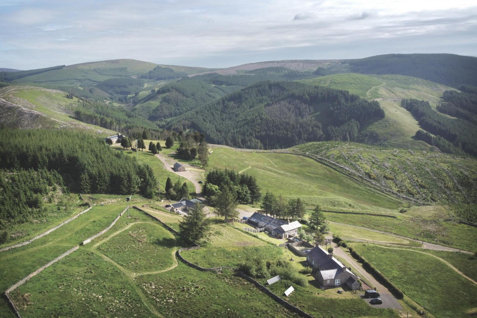 Aerial view of holiday cottages amid green hilly landscape
