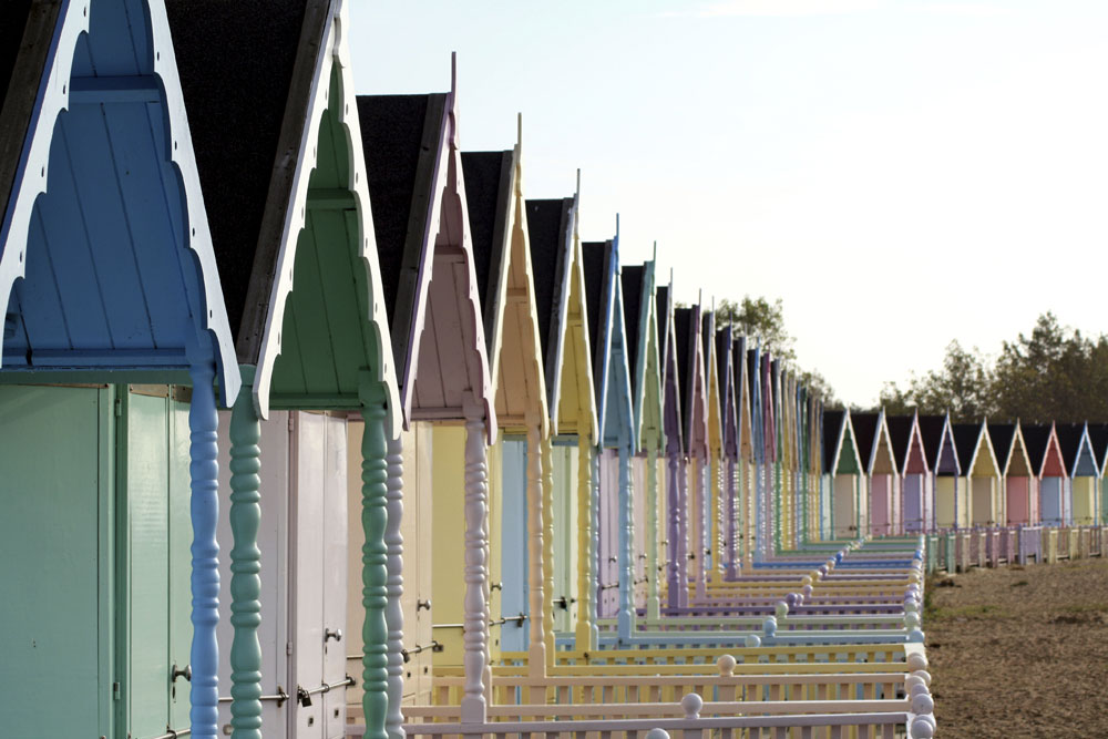 Pastel coloured beach huts lined-up on Mersea Island