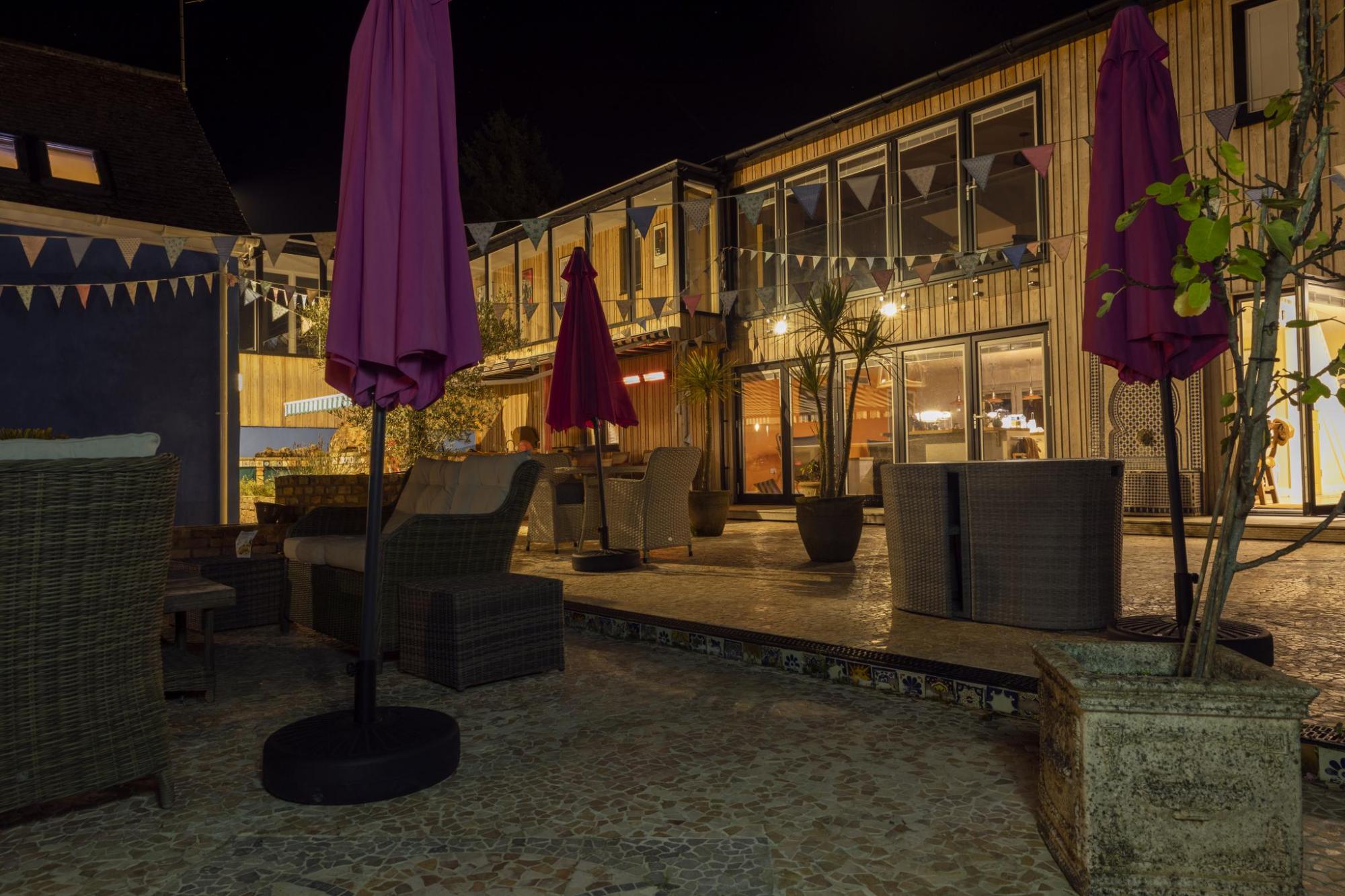 A wooden socialising deck outside a modern-looking bed and breakfast at night