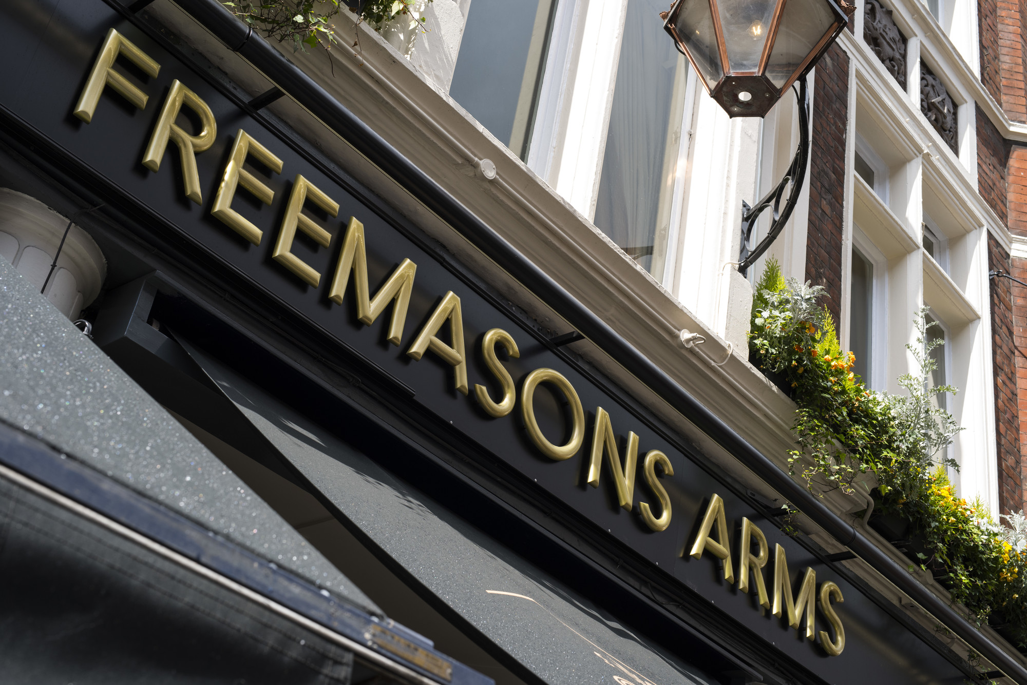 Freemasons Arms pub fascia with gold lettering on sleek black background