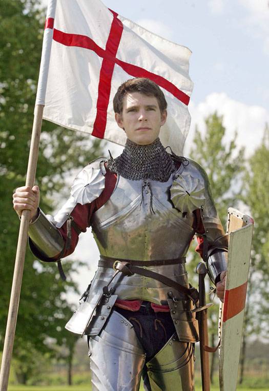 A man dressed as St George wearing a suit of armour and holding an English flag
