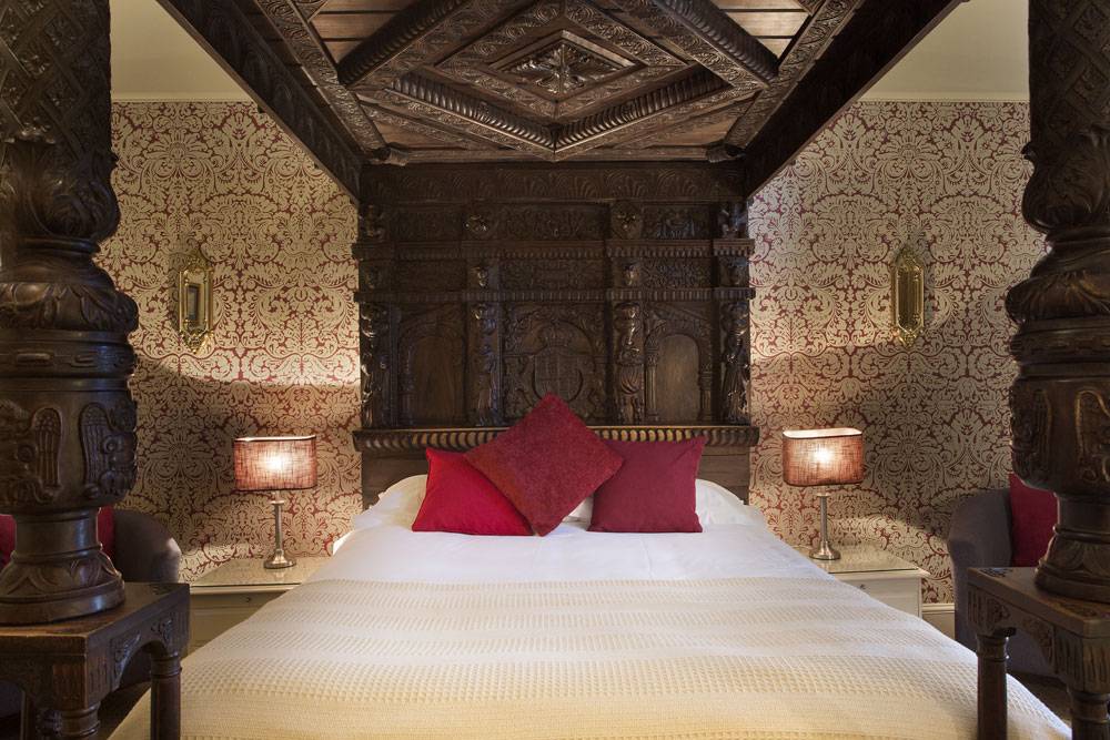 A four-poster bed with red cushions, just one of the George Hotel's luxury rooms