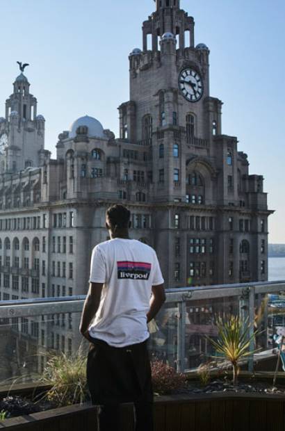 Young man standing on restaurant roof terrace near Royal Liver Building, Liverpool