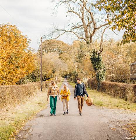 A group of people walking down a road in the countryside in Autumn.