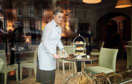 Waitress standing at a table setting up afternoon tea