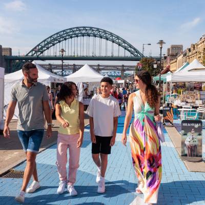 A family visit a Sunday market by the river Tyne in Newcastle upon Tyne