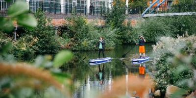 Two people stand-up paddleboarding through Sheffield