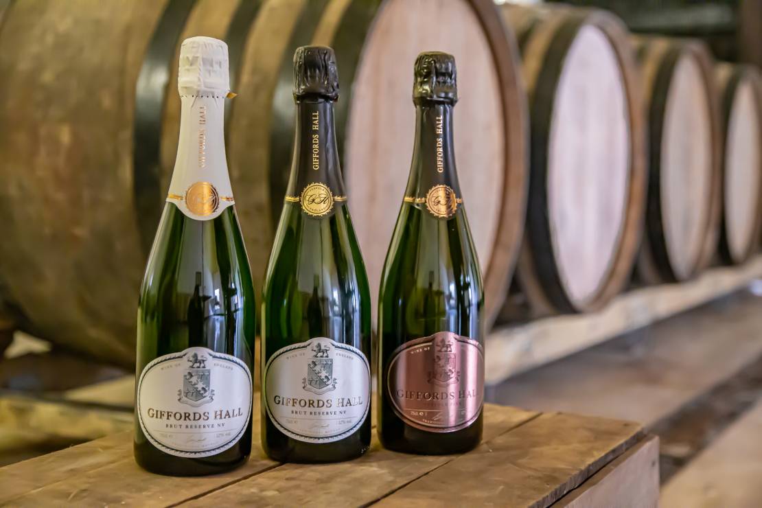 Three Giffords Hall sparkling wines in front of barrels
