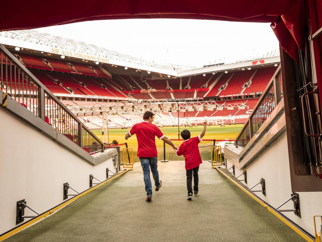 A man and boy in stadium tunnel looking out to pitch 