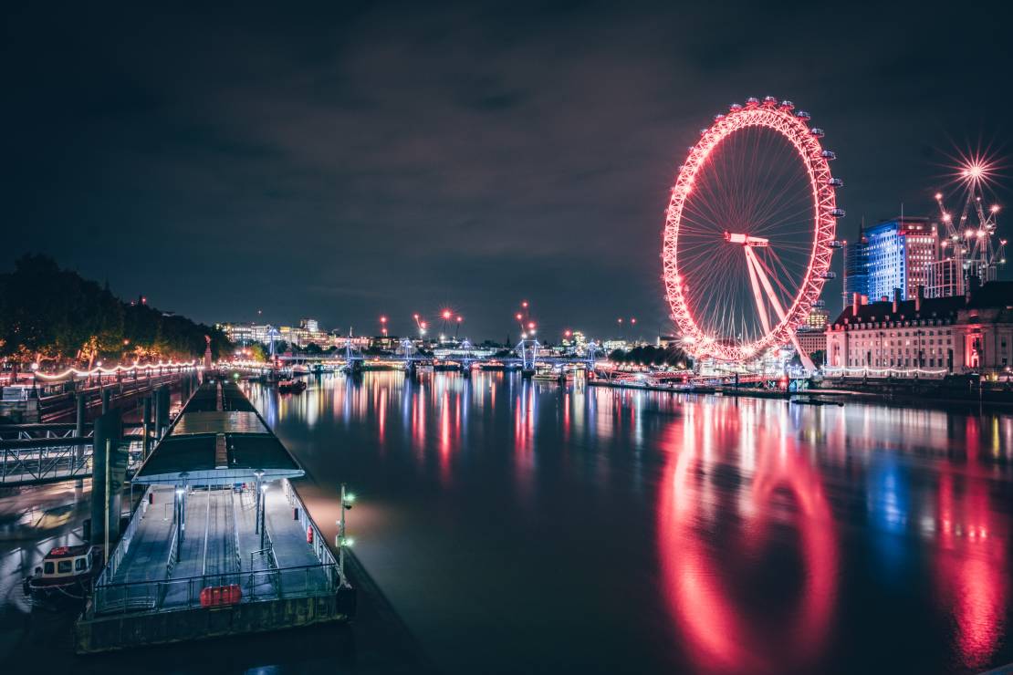 London Eye lit up, in red, at night across the river