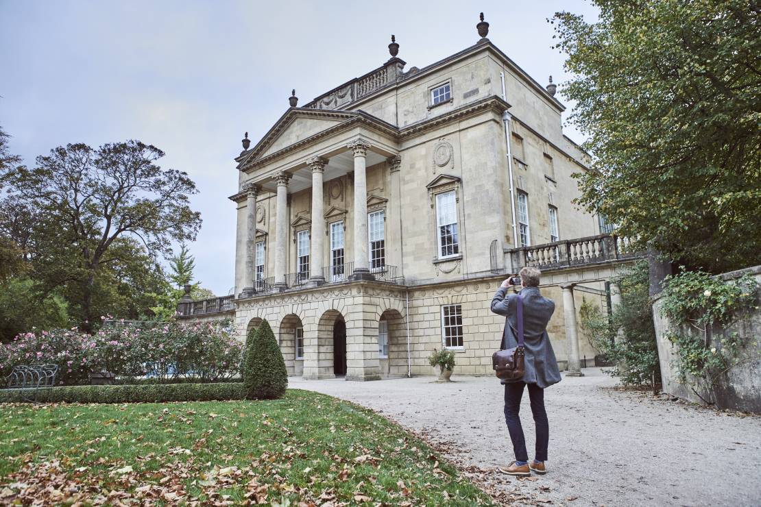 Rear view of man taking picture of The Holburne Museum, Bath, Somerset, England.