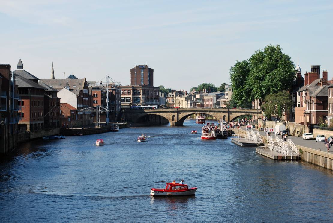 River in centre of York with motor boats and bridge in the distance