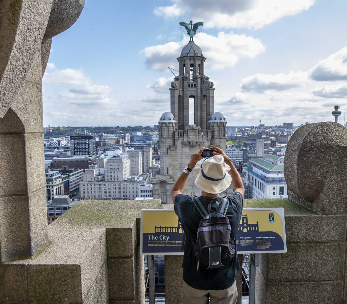 Gentleman photographing the tower in the skyline from the roof of the Royal Liver Building 360, Merseyside