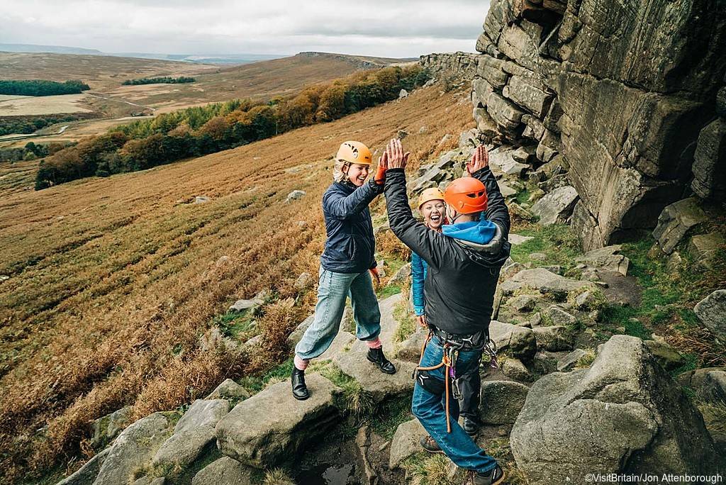Three people in climbing gear, two women and a man, at Stanage Edge, Peak District, Derbyshire, England.