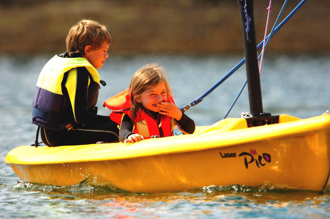 Two children sitting inside sailing boat