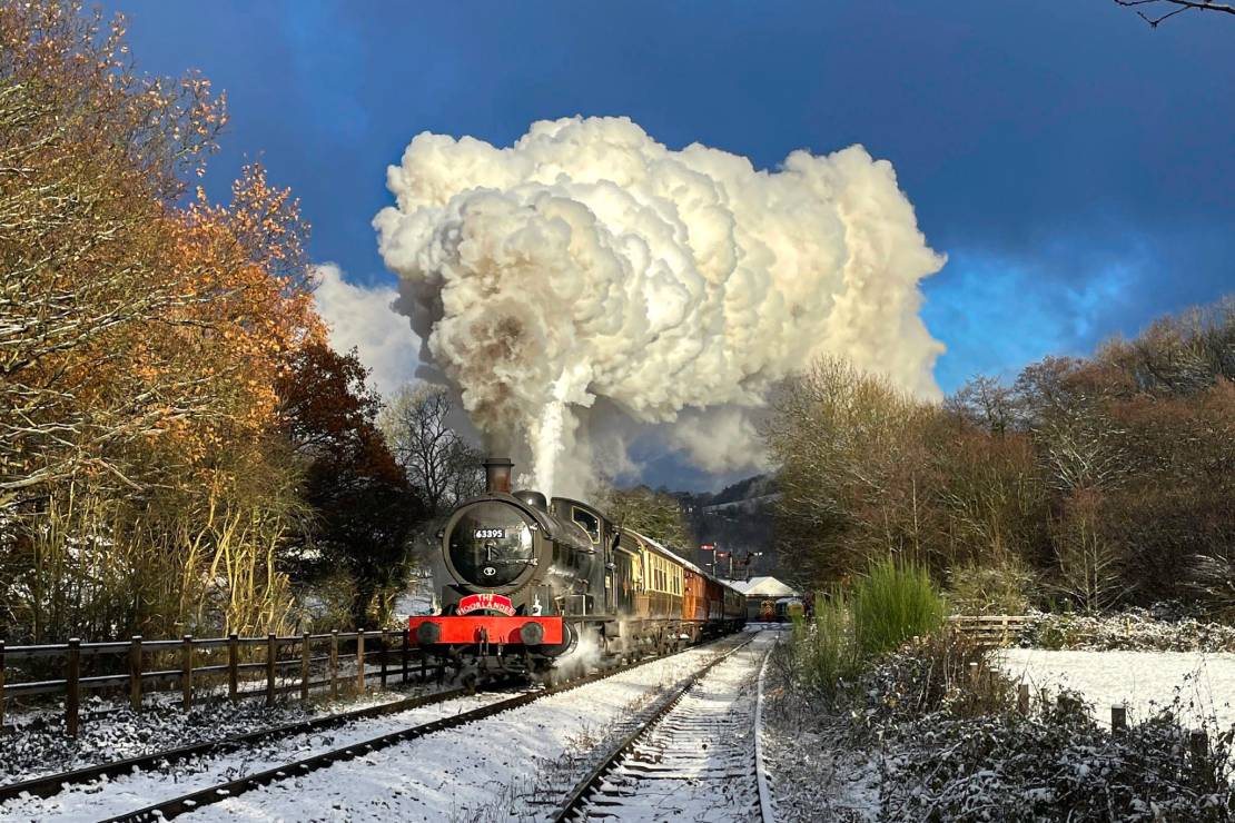 A steam train travels through a snow-covered landscape
