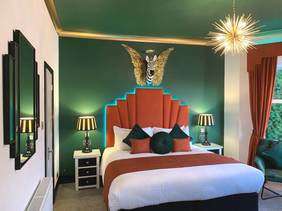 Art Deco-style bedroom with green walls and orange bed frame