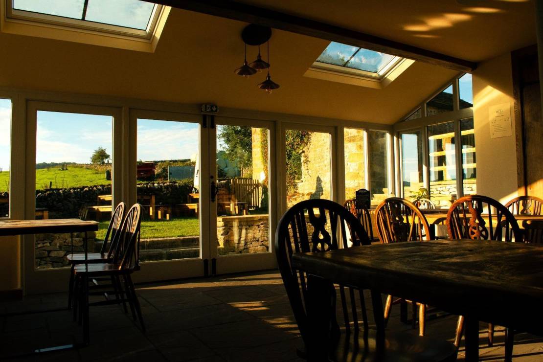 Interior of a pub conservatory dining room at sunset with light streaming in 