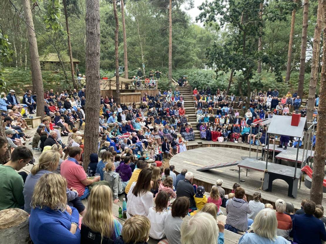 Audience sitting in an outdoor theatre in the woods