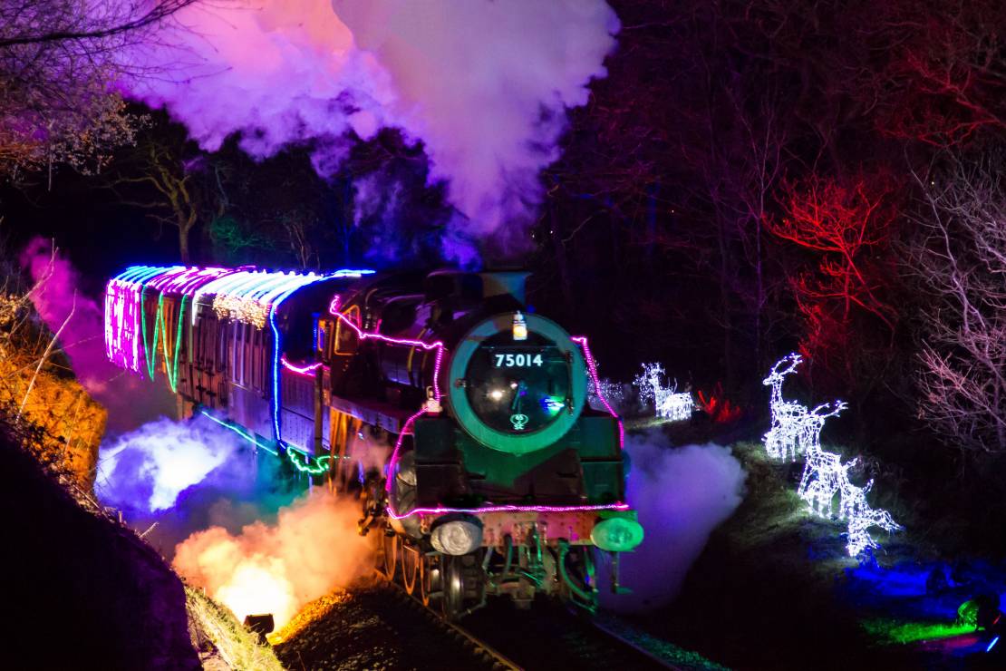 Steam train covered in neon lights making its way through the forest
