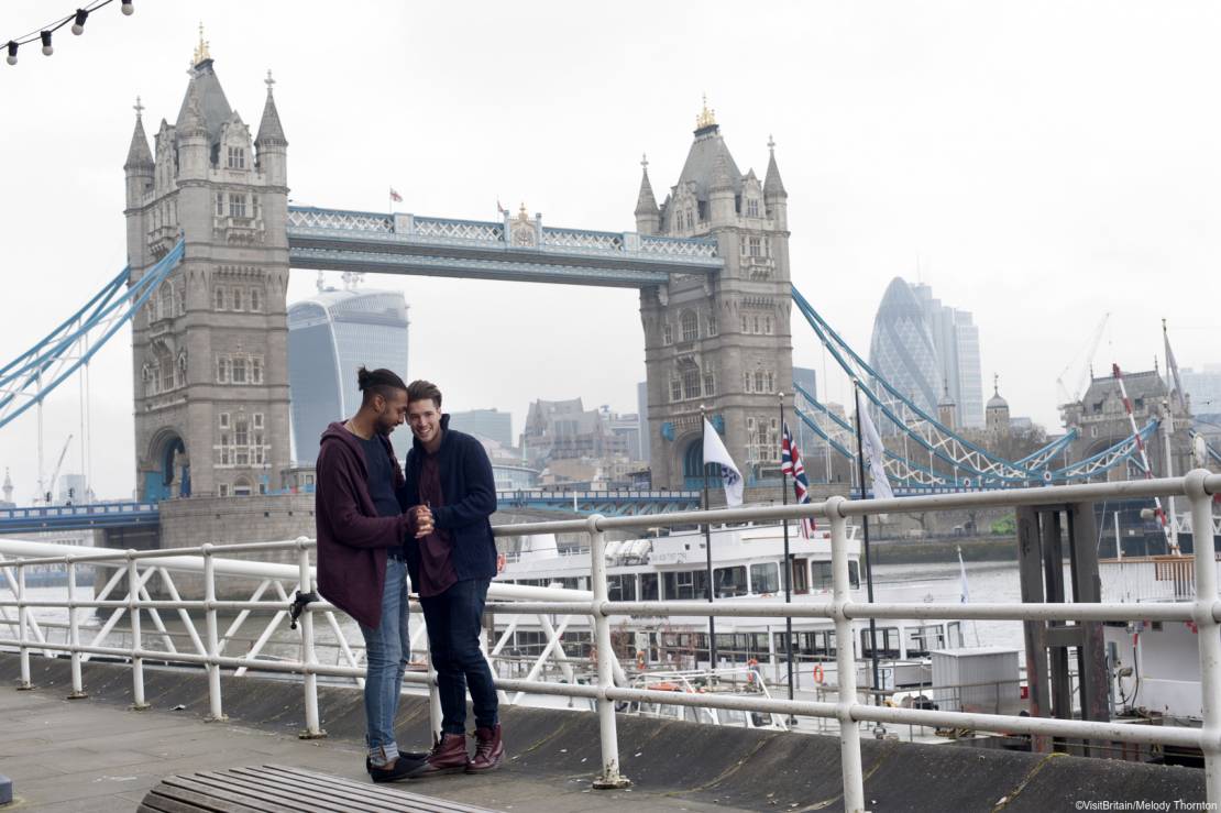 Gay couple standing by the River Thames near Tower Bridge, London.