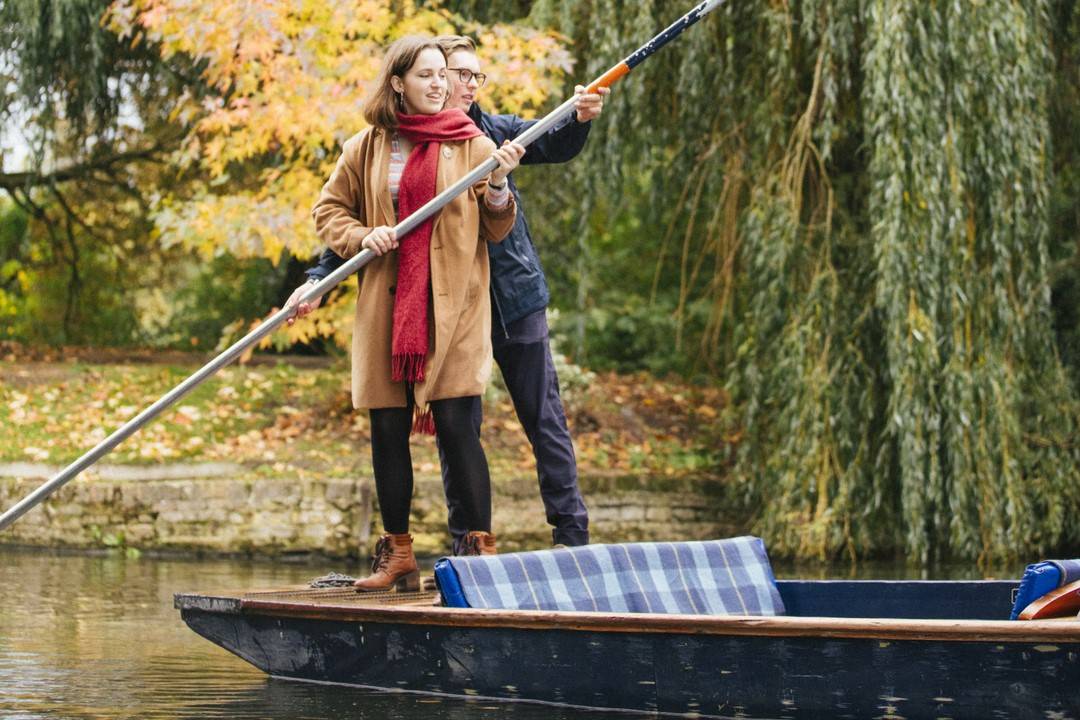 Man and a woman punting on the River Cam in autumn, Cambridge, Cambridgeshire, England.