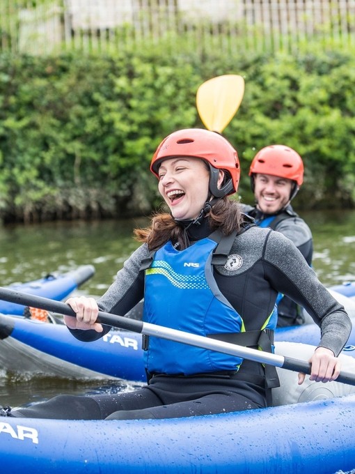 People smiling and laughing while kayaking down a river in Chester