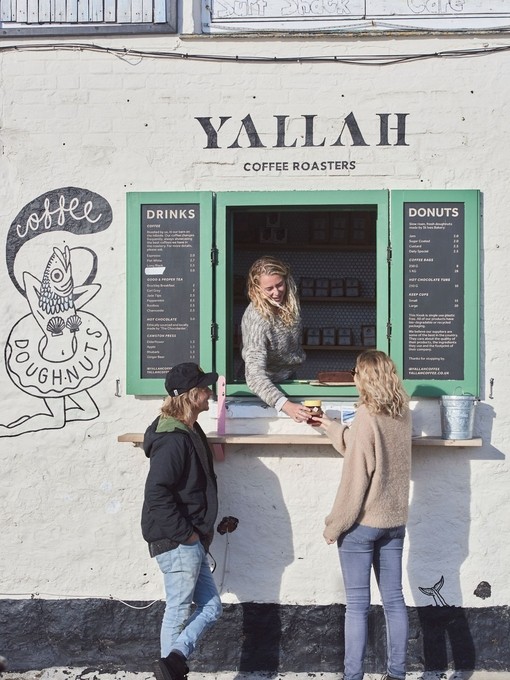 Woman serving coffee through window to two customers