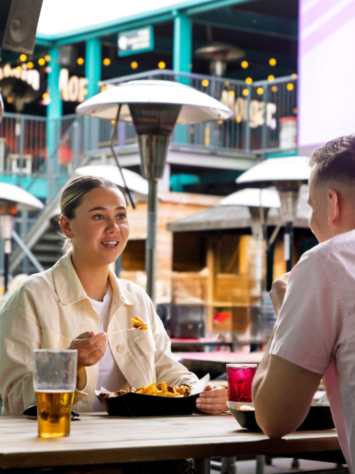 Two people enjoying food and drinks at an outdoor cafe.