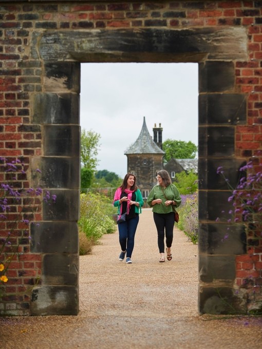 Two women walking toward archway, RHS Bridgewater