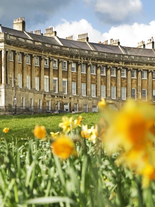 External view of regency style building of the Royal Crescent, Bath through a field of blurred out daffodils in the foreground,