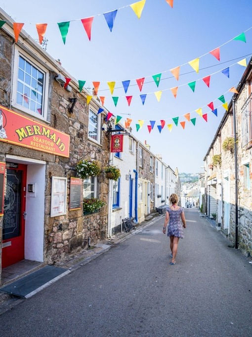 Woman walking down a street below rainbow bunting