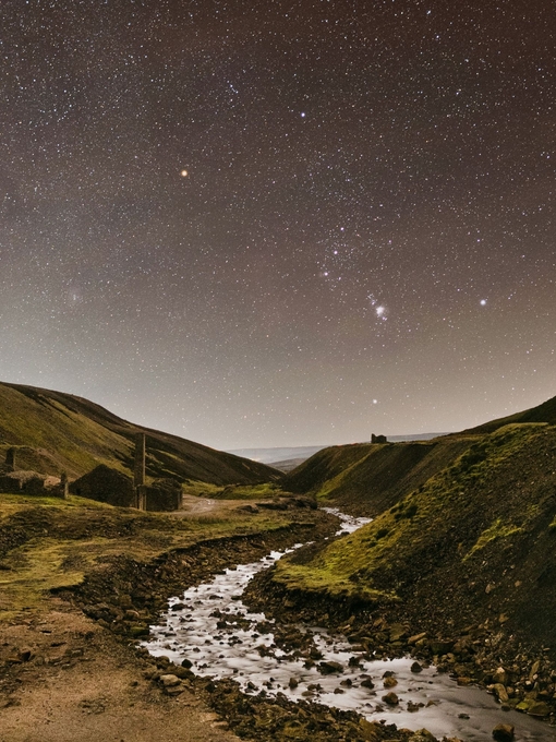 A stream winding through the mountains under a starry sky.