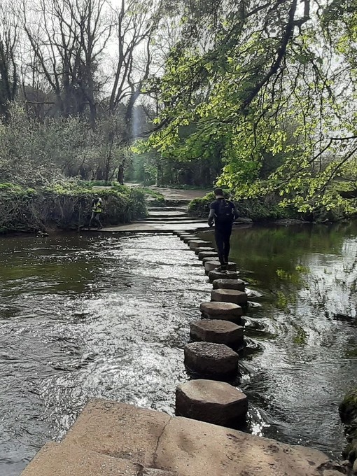 Man walking over stepping stones across a river