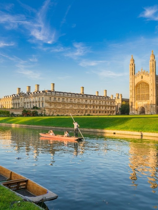 People punting along a river next to a college and chapel.