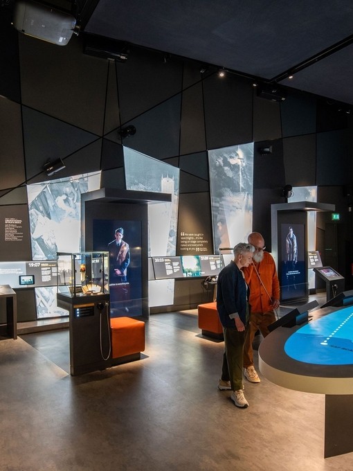 A man and a woman listening to an interactive exhibiton